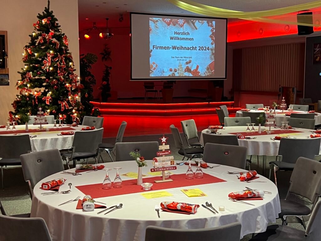 Firmen-Weihnachtsfeier mit runden Tischen, weihnachtlicher Deko und Eindeckung mit Weihnachtsbaum