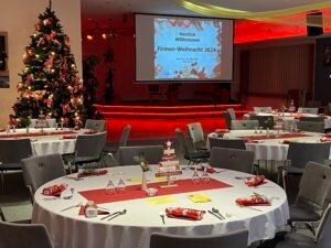 Firmen-Weihnachtsfeier mit runden Tischen, weihnachtlicher Deko und Eindeckung mit Weihnachtsbaum